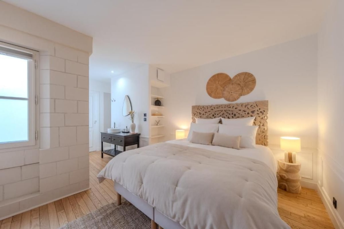 A bedroom with a large bed, a bedside table, a dresser, and a wall-mounted mirror.
