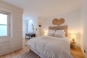 A bedroom with a large bed, a bedside table, a dresser, and a wall-mounted mirror. - La Salamandre (Orléans)