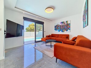 A modern living room with a large orange sofa, a coffee table, and a flat-screen TV mounted on the wall. - Aloa II by Interhome (Brač/Splitska)