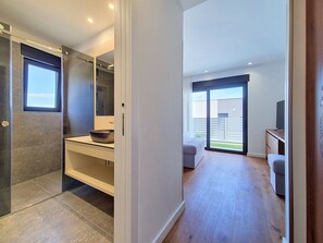 A modern interior with a glass shower, a kitchen area with a sink and countertop, a dining area with a table and chairs, and a large sliding glass door leading to a balcony. - Aloa II by Interhome (Brač/Splitska)