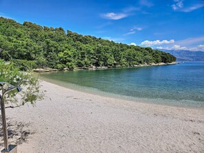 A beach with clear water, a sandy shore, and a forested hillside. - Aloa II by Interhome (Brač/Splitska)