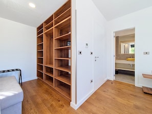 A room with a wooden shelving unit, a white door, and a bathroom with a mirror and sink. - Aloa III by Interhome (Brač/Splitska)