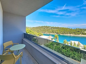 A balcony with a table and chairs, overlooking a coastal landscape with trees and a body of water. - Aloa III by Interhome (Brač/Splitska)