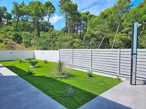 A modern outdoor patio with a neatly trimmed lawn, a white fence, and a metal gate. - Aloa IV by Interhome (Brač/Splitska)