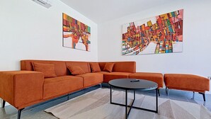 Uma sala de estar moderna com um sofá modular, uma mesa de centro redonda e quadros abstratos nas paredes.