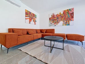 A modern living room with a sectional sofa, a round coffee table, and abstract paintings on the walls. - Aloa IV by Interhome (Brač/Splitska)