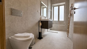 A modern bathroom with a toilet, a sink, a mirror, and a shower. - Studio apartment | Prime location (Câmara de Lobos)