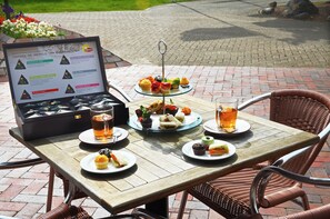 Een tafel met een menukaart, belegde broodjes, cupcakes en een drankje.