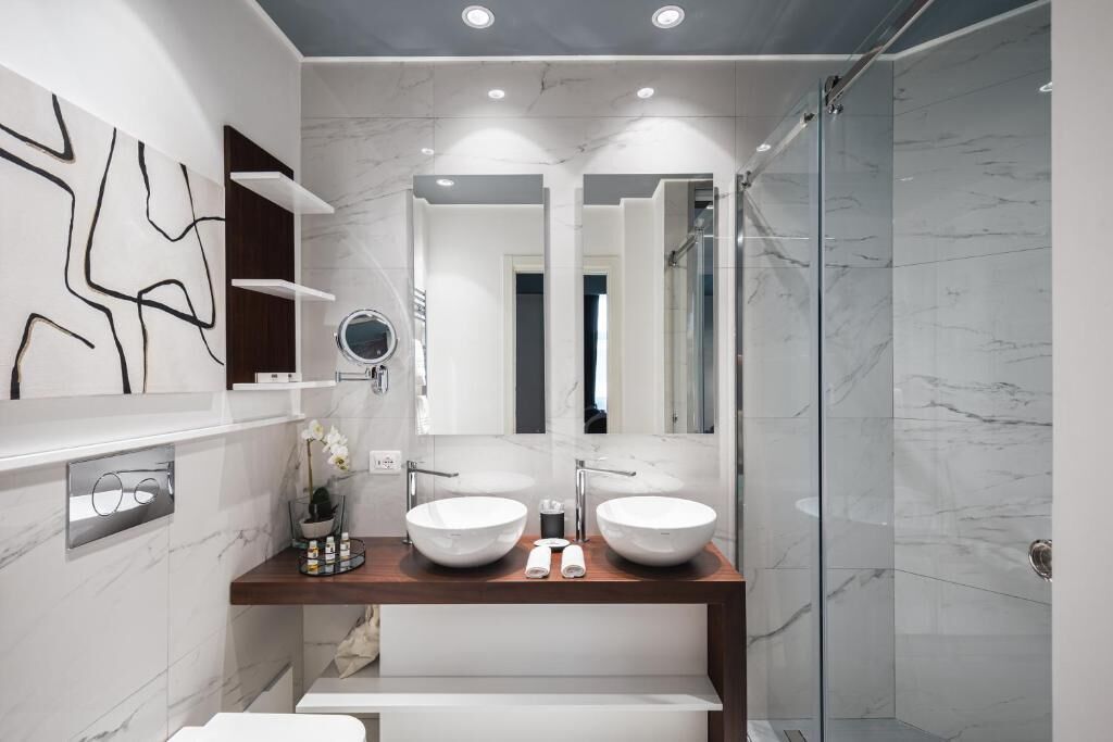 Ein modernes Badezimmer mit zwei Waschbecken, einem großen Spiegel und einer Dusche.