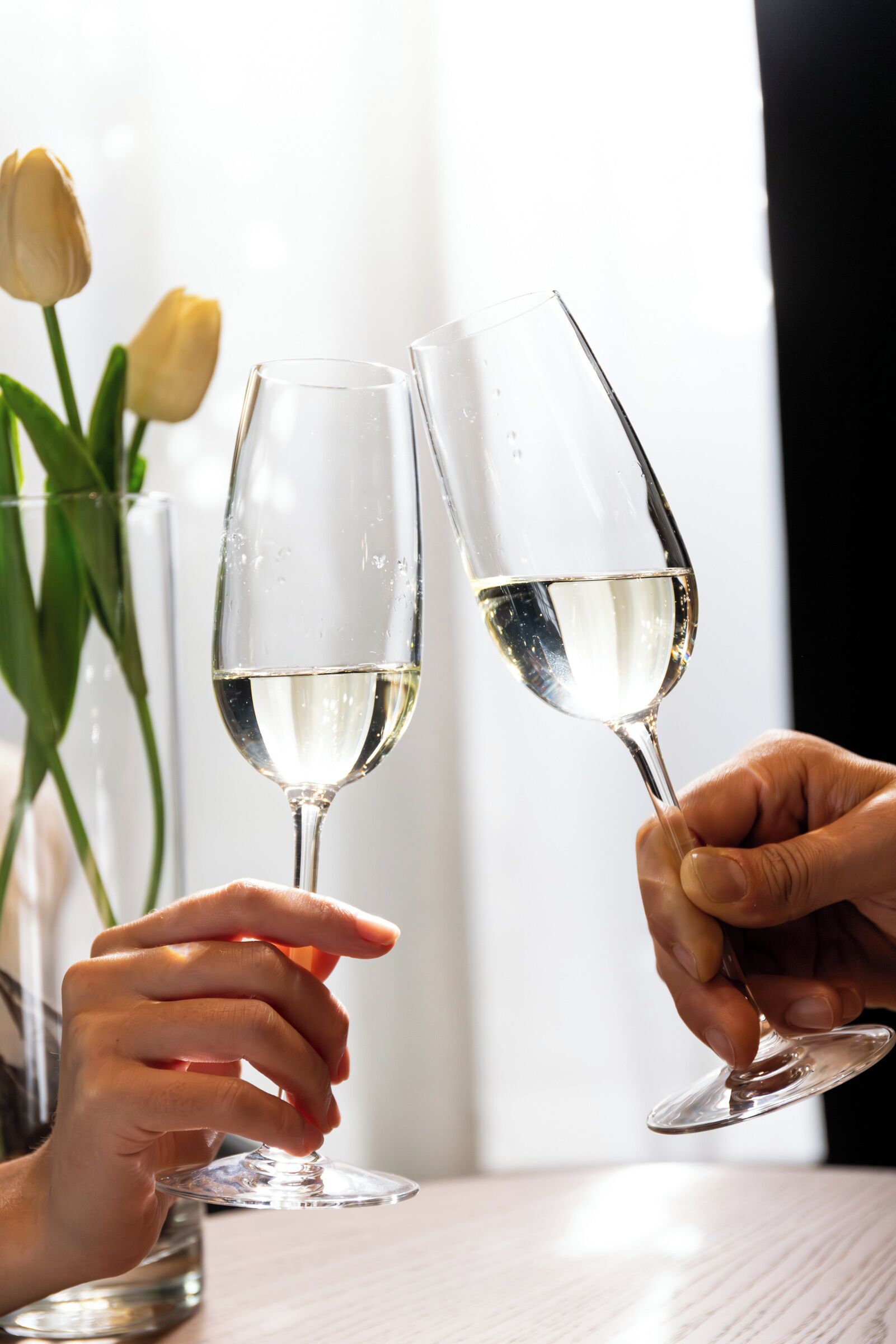 Two champagne flutes being clinked together.