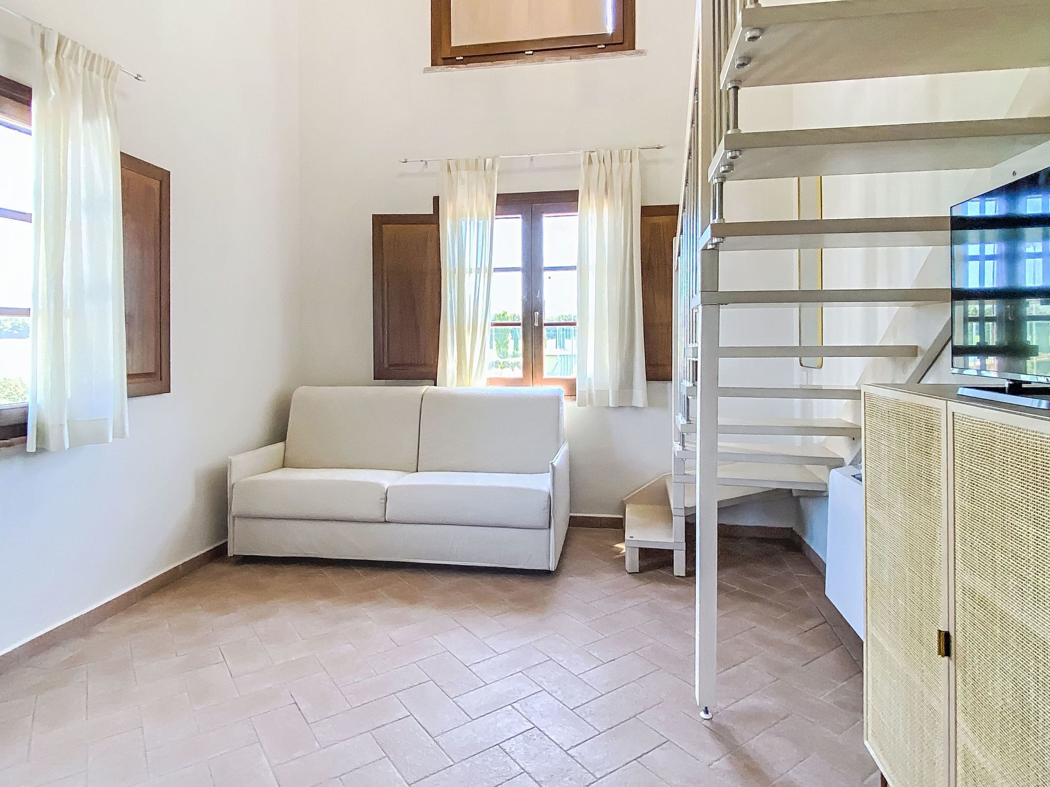 Una habitación con sofá, una escalera y televisor.