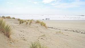 Une plage de sable avec des dunes et un ciel dégagé.