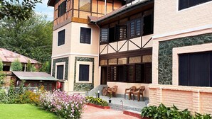 A two-story building with a balcony, a garden with flowers, and a small outdoor seating area. - Lakshmi Guest House (Srinagar)