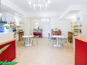 Ein modernes Interieur mit zwei runden Tischen, Stühlen, einer Pendelleuchte und Regalen mit Flaschen.