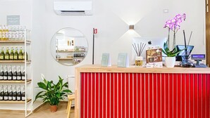 A reception desk with a red panel, a mirror, a wall-mounted air conditioner, and shelves with bottles. - Casale Bolgherese by Interhome (Bolgheri)