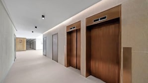 A modern hallway with a light-colored floor, wooden doors with labels, and recessed ceiling lighting. - emaro hostel (Dubai)