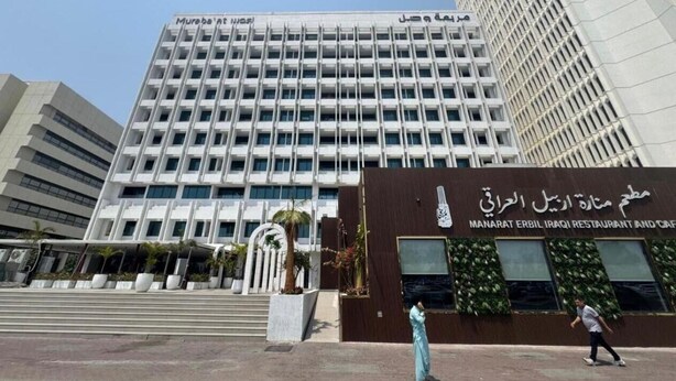 A modern building with multiple floors, a prominent entrance with steps, and a sign for 'Manarat Erbil Iraqi Restaurant and Cafe'. - emaro hostel (Dubai)