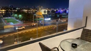 A balcony with a view of a cityscape at night, including a road and buildings. - emaro hostel (Dubai)