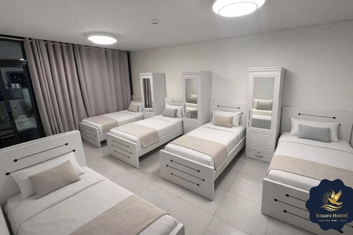 A hotel room with four beds, a large mirror, and a view of the city at night.