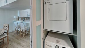 Eine kompakte Küche mit weißen Schränken, einer Mikrowelle und einer integrierten Waschmaschine und einem Trockner.