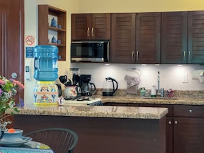 Eine Küche mit Granit-Arbeitsplatten, Wasserspender, Mikrowelle und Kaffeemaschine.