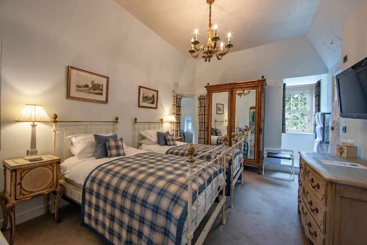 A bedroom with a large bed, bedside lamps, a mirror, a dresser, and a television.