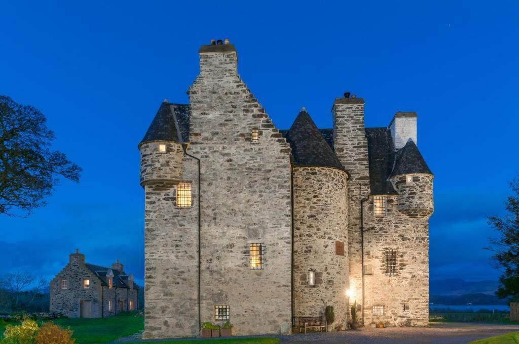 A stone castle with multiple towers and a well-lit entrance.