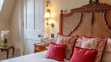 A hotel room with a large bed, a wooden headboard, a bedside table with a lamp, and a window with curtains.