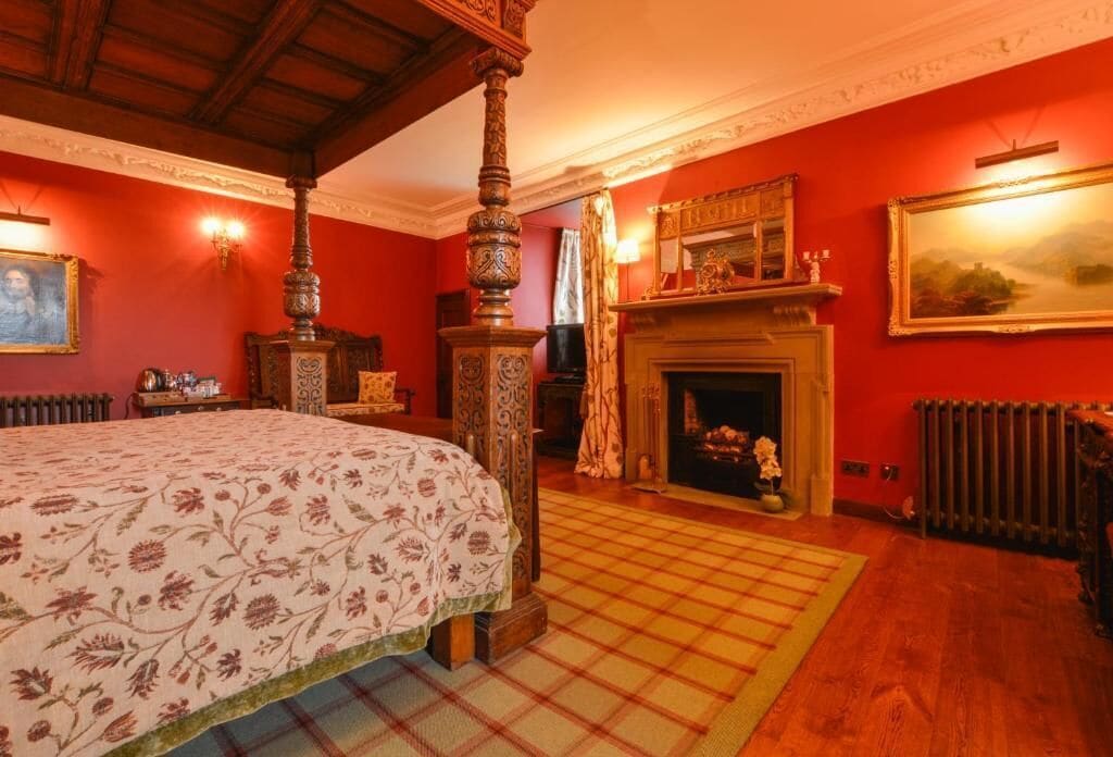 Une chambre avec un grand lit, une cheminée, un miroir et un tableau au mur.