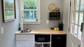 A compact kitchen with a sink, microwave, and dishwasher, a window with a view, and a door with a glass panel.