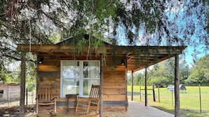 A wooden cabin with a porch, two rocking chairs, and a large window.