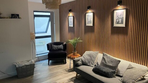 Ein modernes Wohnzimmer mit Sofa, Sessel und Holzvertäfelung.