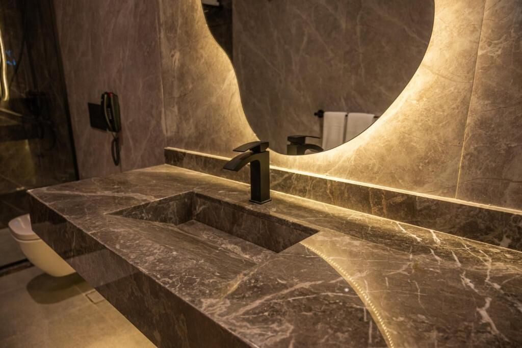 A modern bathroom with a marble sink, a large mirror, and a telephone.