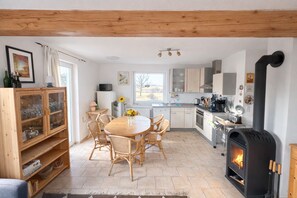 Cucina con isola centrale, sedie di legno, tavolo da pranzo e vista sull'esterno.