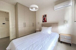 Un dormitorio con cama, armario, mesita de noche y unidad de aire acondicionado.