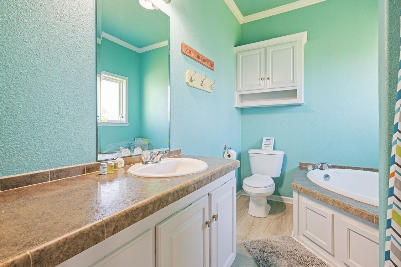 Une salle de bain avec deux lavabos, des toilettes et une baignoire. Il y a une fenêtre et un meuble au-dessus des toilettes.
