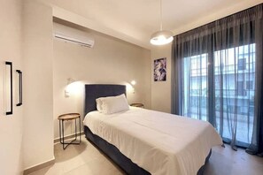 A bedroom with a bed, bedside tables, a wall-mounted air conditioner, and a large window with curtains. - Athenean Gem Near Athens Metro Mall-B2 (Ilioupoli)