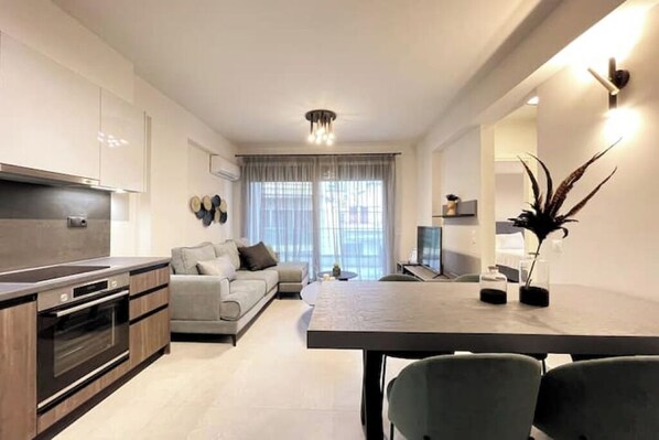 A modern kitchen with a dining area, a sofa, and a TV. - Athenean Gem Near Athens Metro Mall-B2 (Ilioupoli)