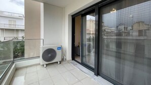 A balcony with a glass railing, a window, and a large air conditioning unit. - Athenean Gem Near Athens Metro Mall-B2 (Ilioupoli)
