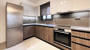 A modern kitchen with stainless steel appliances, wooden cabinets, and a built-in oven. - Athenean Gem Near Athens Metro Mall-B2 (Ilioupoli)