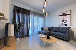 Ein modernes Wohnzimmer mit einem grauen Sofa, einem Couchtisch, einem Fernseher und einem Bild an der Wand.