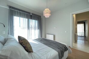 Ein Schlafzimmer mit Bett, einer Hängelampe, einem Fenster mit Vorhängen und einer Heizung.