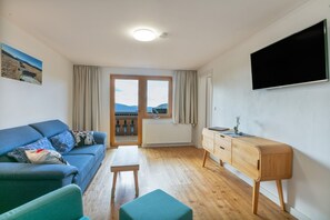 Una sala de estar moderna con un sofá, un escritorio de madera y vistas a través de un ventanal.