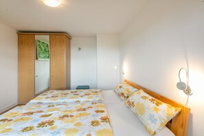 Un dormitorio con dos camas, un armario y una lámpara fijada a la pared.
