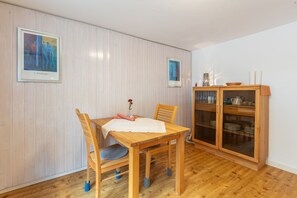 A dining area with a wooden table, chairs, and a cabinet with glass doors. - Alpenblick Apartment (Todtnau)