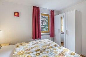 A bedroom with a bed, a window with curtains, a wardrobe, and a small painting on the wall. - Wiesentalblick Apartment with Mountain View and Balcony (Todtnau)