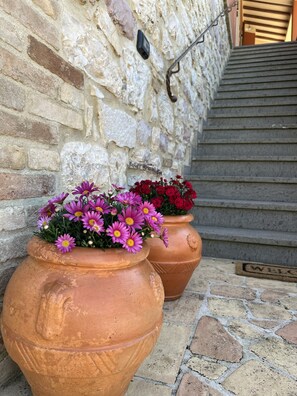 Terrakotta-Pflanzgefäße mit Blumen an einer Steinsäule.
