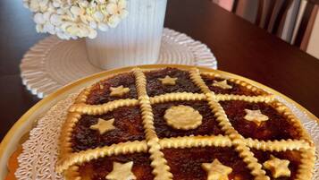 A pie with star-shaped cutouts on a decorative plate, a white vase with flowers, and a dining table.