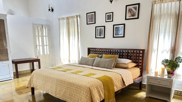 A neatly arranged bedroom with a bed, bedside tables, a nightstand, and a window with curtains.