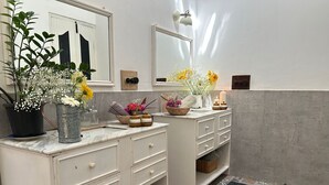 A bathroom with two sinks, a mirror, a light fixture, and a patterned floor.